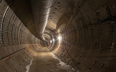 Empty subway underground tunnel under construction. Large temporary ventilation pipe under the...