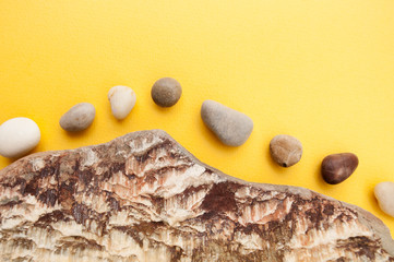 Minimalistic composition of multi-colored sea pebbles on a bright yellow background..