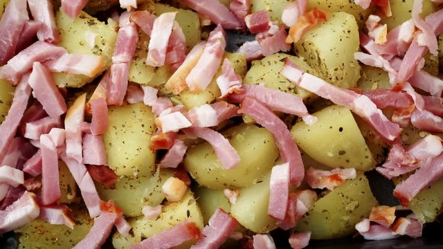Peeled potatoes with spices, becon meat and onion slices ready to be roasted close up. Food background. Dolly shot 4K ProRes HQ codec