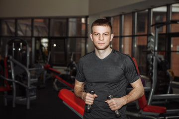 Fototapeta na wymiar Young muscular man boxer, boxing gloves. Young man in the gym, boxing with dumbbells.