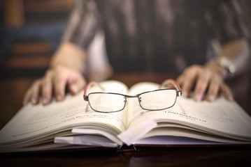 glasses on book with hand of old man background