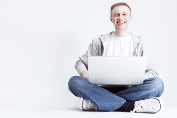 Modern Youth Lifestyle Ideas and Concepts. Smiling Handosme Caucasian Man with Laptopp Chatting. Posing Against White Background.