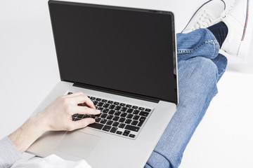 Closeup Portrait of Caucasian Man Hands Working with Laptop Computer and Lying on Floor with Legs Lifted on Box.