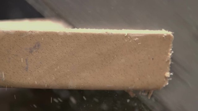 Carpenter using a handsaw and sawing a wooden plank in slow motion