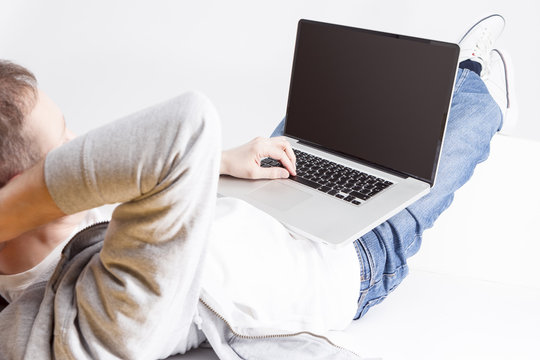 Closeup Portrait of Caucasian Man Working with Laptop Computer and Lying on Floor with Legs Lifted on Box.