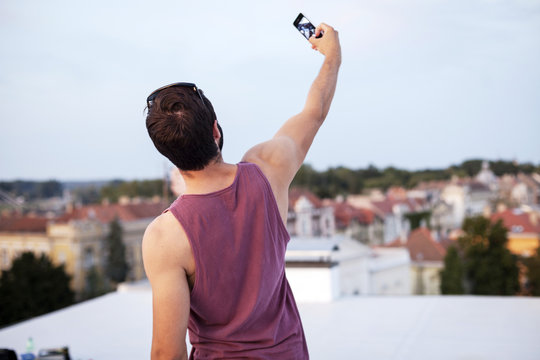 Young man taking a self-portrait on roof terrace