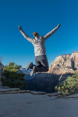 Fototapeta premium Leaping for Joy After Climbing Up to a Canyon