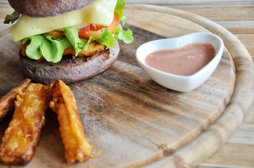 knife on hamburger and french fries on the wooden plate, focus at hamburger
