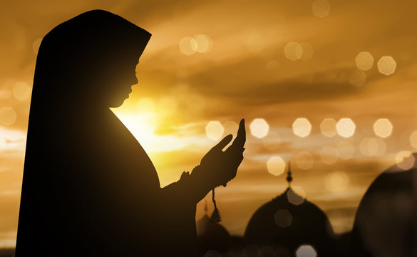 Silhouette of muslim woman praying with prayer beads