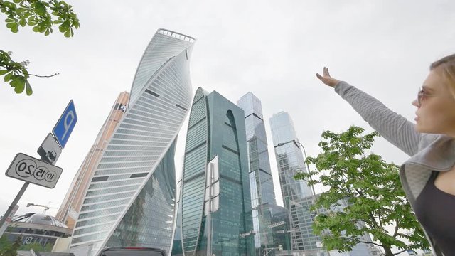 A blonde girl admires skyscrapers and high-rise buildings in the city center. Shooting in slow motion.