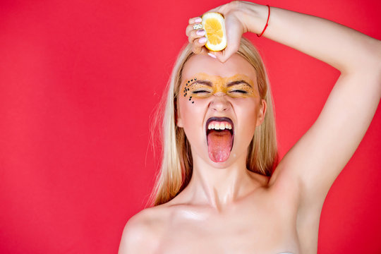 pretty blonde woman with creative fashionable makeup drink lemon, vitamin
