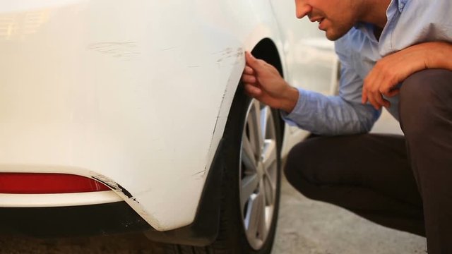 looking at a damaged vehicle. man inspects car damage after an accident