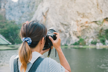 Back of professional travel photographer with camera while shooting landscape..Young woman taking photo of mountain..woman photographer taking photo at the lake.