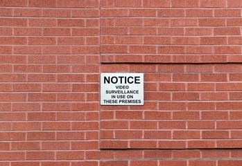 Brick wall with surveillance notice sign 