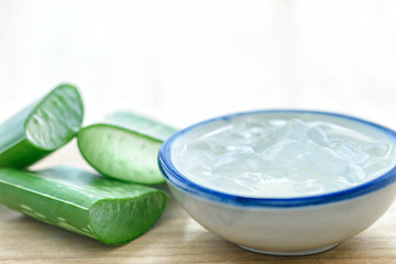 Aloe vera gel on bowl with fresh aloe vera leaves on wooden