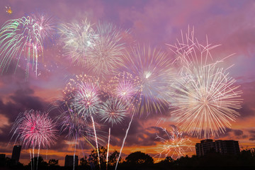 Beautiful colorful holiday fireworks in the sunset/evening sky with majestic clouds, long exposure. Concept of American Independence celebration. Happy Independence Day or Fourth of July banner.