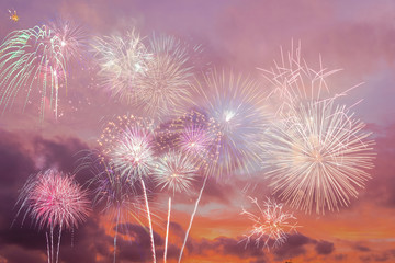 Beautiful colorful holiday fireworks in the sunset/evening sky with majestic clouds, long exposure. Concept of American Independence celebration. Happy Independence Day or Fourth of July banner.