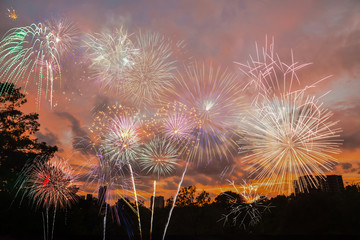 Beautiful colorful holiday fireworks in the sunset/evening sky with majestic clouds, long exposure. Concept of American Independence celebration. Happy Independence Day or Fourth of July banner.