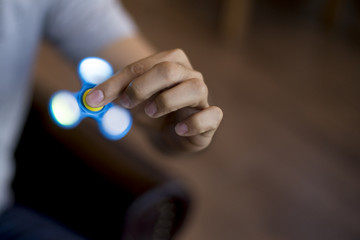 Young man playing with a fidget spinner with light