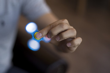 Young man playing with a fidget spinner with light