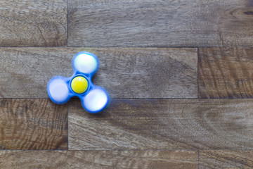 Play Fidget spinner spinning on wood background With Light