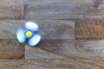 Play Fidget spinner spinning on wood background With Light