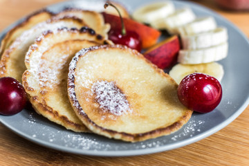 Sweet pancakes with berries and fruits on a wooden background