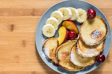 Sweet pancakes with berries and fruits on a wooden background