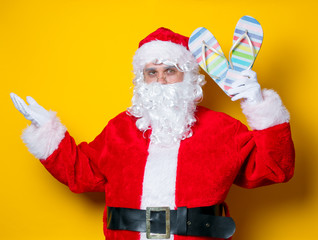 Fototapeta na wymiar Funny Santa Claus holding flip flops
