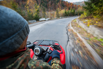 View from the atv at the road. Man drives an off-road vehicle at a speed. Colorful trees by the roadside. Point of view shot from a moving vehicle © anatoliy_gleb