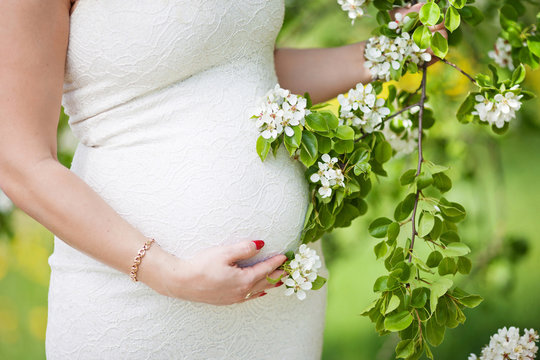 Close-up image of pregnant woman touching her belly with hands
