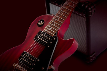 Fototapeta na wymiar Red electric guitar and classic amplifier on a dark background