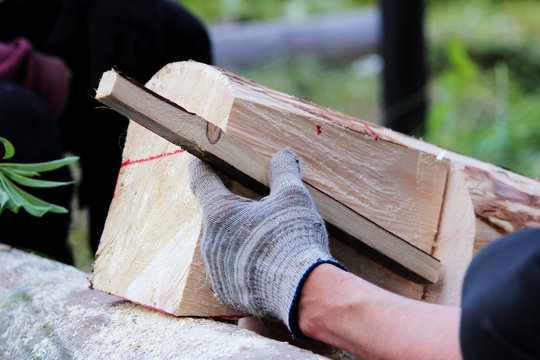 The worker makes a marking on the log before the building of the blockhouse and uses wooden dowel as a ruler markup before working to hacket