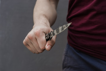 Young guy with a knife about to attack, over dark background.