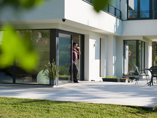 man drinking coffee in front of her luxury home villa