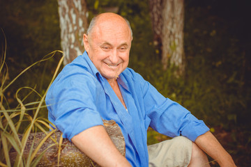 Naklejka na ściany i meble Portrait happy mature man in blue shirt and casual style on a nature