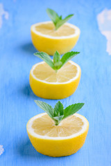 Cut the lemons with sprigs of mint on a blue background. The lemon and mint on old painted surface blue color