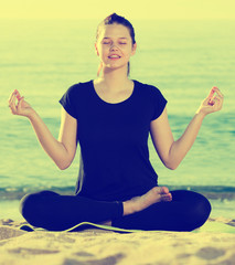 Adult female in black T-shirt is sitting and practicing asana