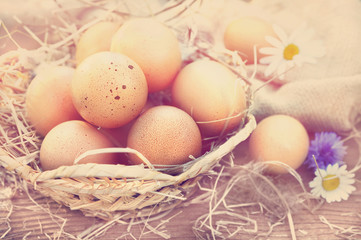Basket of fresh organic farm eggs on rustic background, selective focus, toned
