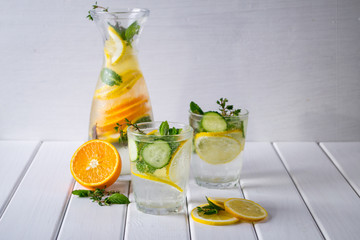 Mineral water with a lemon slices and mint on white wooden background