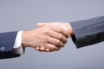 Handshake of businessman and businesswoman on light gray background