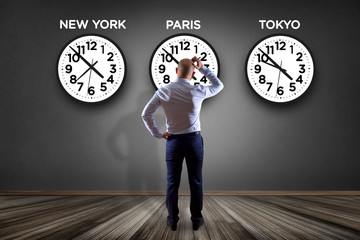 Businessman in front of a wallwith clocks of different country - Jetlag concept