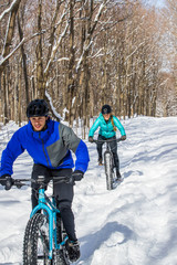 Attractive couple riding fat bikes in the snow