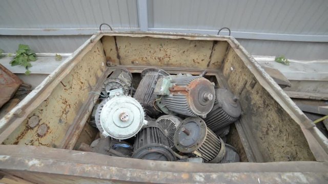 Used, broken and not working electric motors. Electric motors are piled in a metal container