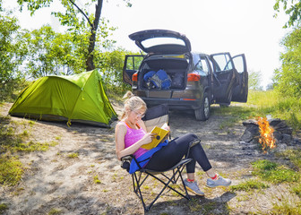 Young alluring blonde woman reading book in outdoor chair