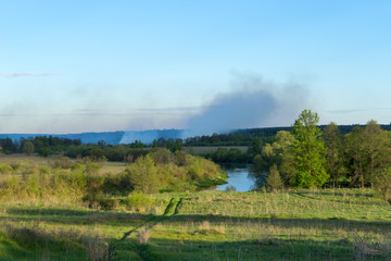 View on river valley against forest fire background. Bulatovo village, Kaluzskaya region, Russia.
