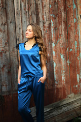 Fototapeta premium Beautiful girl in silk blue clothes,chic, fashion, looking away, standing with hands in pockets, outdoor, street style, walk