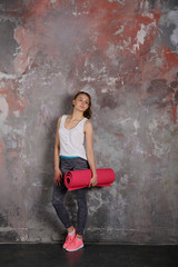 Yoga sport beautiful young woman standing full length, gray background, loft, urban style