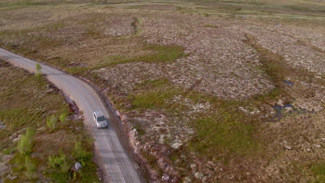 Car driving on rural road over marshlands