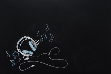 headphones with wire and musical notes drawn on black chalkboard